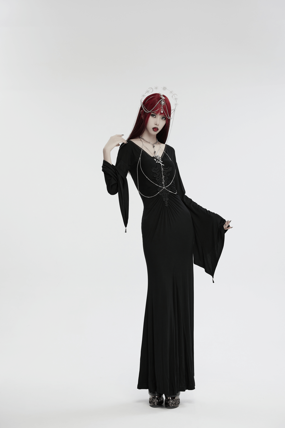Gothic model in a black dress wearing a celestial headpiece with stars, moons, and crystal chains.