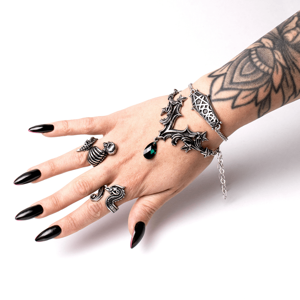 Gothic Ivy Bracelet with green crystal drop charm worn on a hand adorned with gothic rings and tattoos.