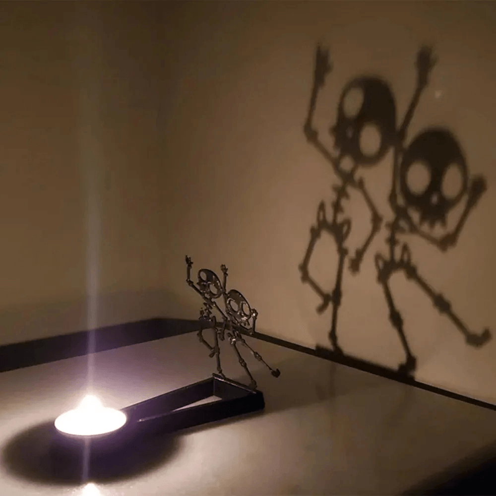 Halloween Shadow Tealight Holder with Metal Scene casting spooky skeleton shadows on the wall.