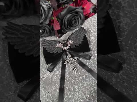 Goth Bat Wing Bow Brooch with Cross Pendant and Ribbon featuring a bat charm and satin ribbons on a dark background.