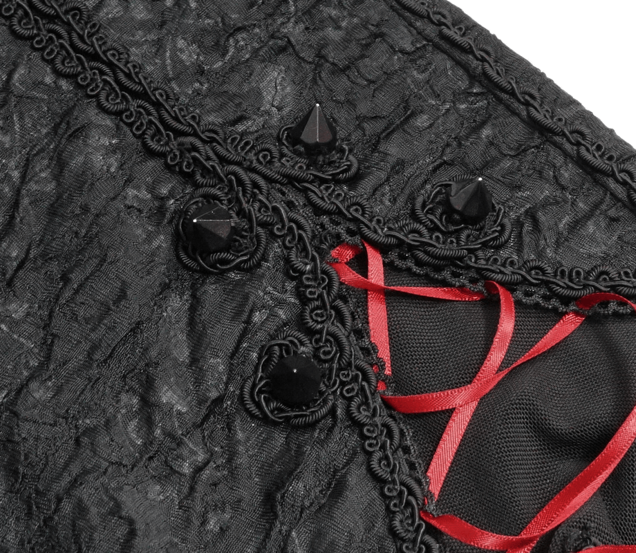 Close-up of gothic black fabric with spikes and red lacing, showcasing stylish details for women's leggings.