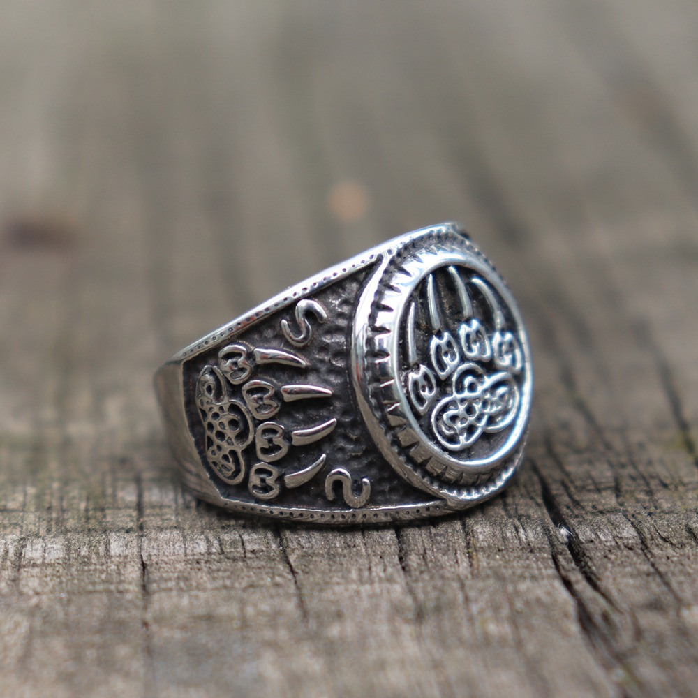 Bear Paw stainless steel talisman ring featuring Celtic knot design on rustic wooden surface.