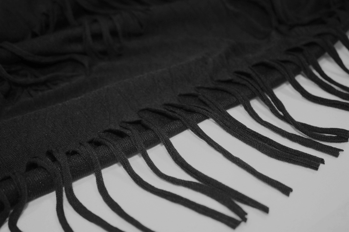 Close-up of black fringe edges on a stylish gothic T-shirt, showcasing trendy texture and design.